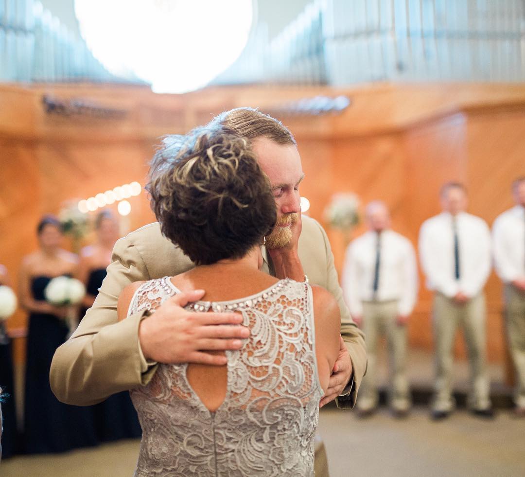 Mom kissing son on cheek at wedding