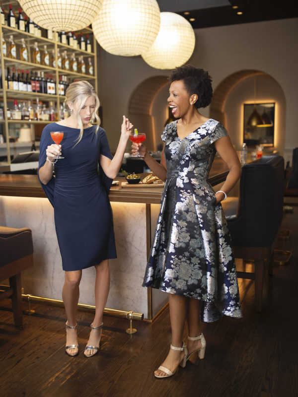 two mother of the brides standing at a bar in cocktail wedding attire