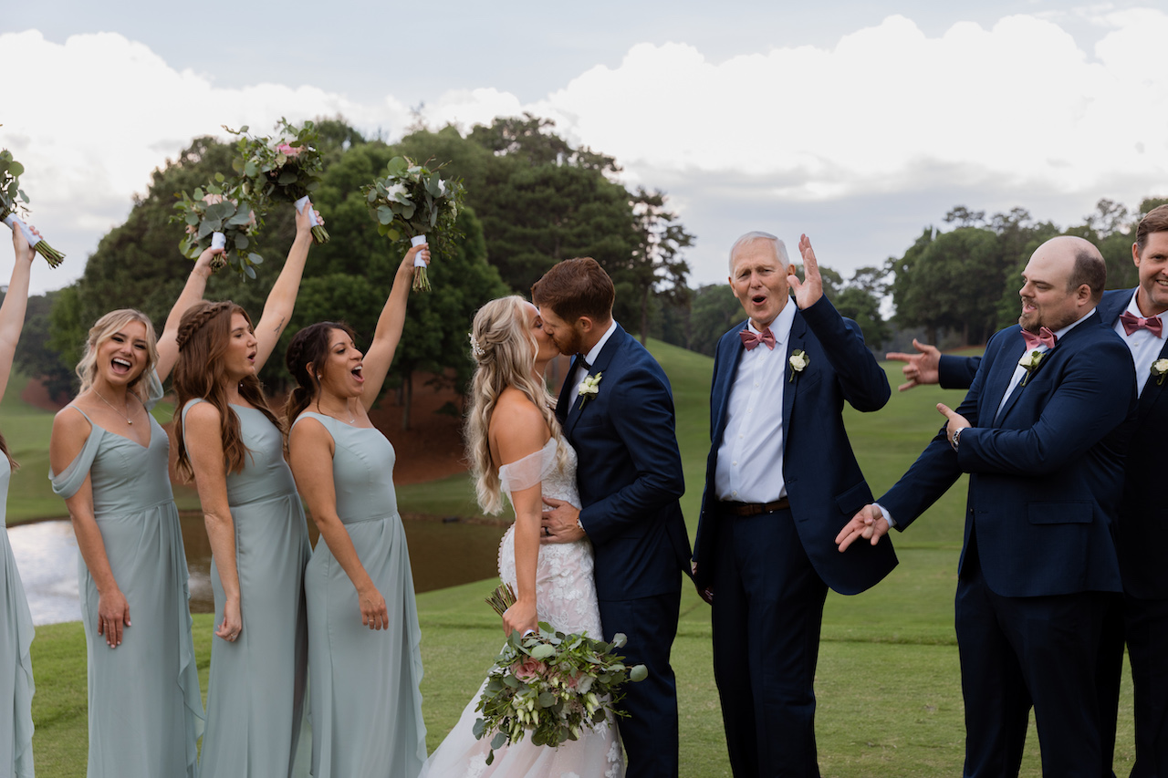 bride and groom kissing and bridal party celebrating - summer wedding in Georgia
