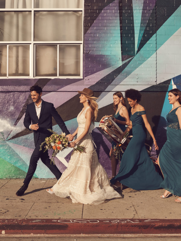 Wedding party walking down sidewalk with band