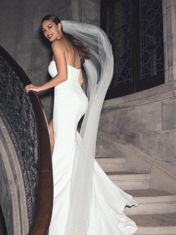 Bride walking up steps in strapless sheath wedding dress with cathedral veil